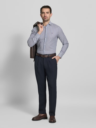 Männermodel trägt Slim Fit Businesshemd aus Baumwoll-Mix von Tommy Hilfiger Tailored, gestreift, Kentkragen, Ganzkörperansicht von vorne.