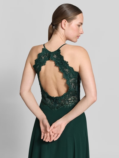 Frauenmodel trägt Abendkleid mit floralem Spitzenbesatz von Vera Mont in dunklem Grün mit Cut Out und Pailletten, Ganzkörperansicht Rückansicht, Chiffon, ärmellos, leicht taillierte Passform