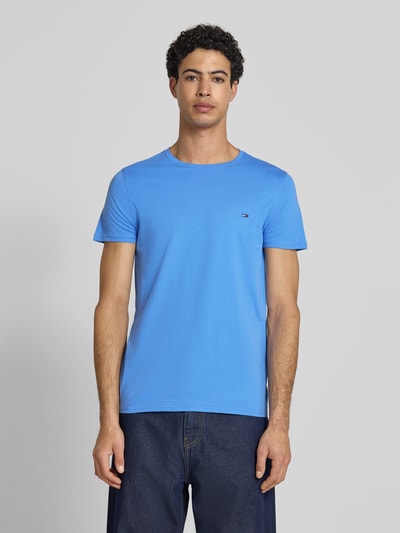 Männermodel trägt Regular Fit T-Shirt aus reiner Baumwolle von Tommy Jeans in Optik: Unifarben, Logo-Stitching, Jersey, Ganzkörperansicht von vorne.
