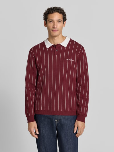 Männermodel trägt Regular Fit Poloshirt mit Logo-Stitching von Les Deux, Baumwolle, Polokragen, Rippen, Bordeaux, Ganzkörperansicht von vorne.