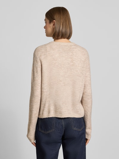 Frauenmodel trägt Loose Fit Strickjacke mit Rundhalsausschnitt Modell 'SIMONI' von ONLY in Beige, grobe Webstruktur, Ganzkörperansicht Rückansicht, Damen Strickjacke von ONLY.