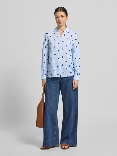 Modelka nosi Regular Fit Bluzkę z dekoltem w serek model 'FABIENNE' od B.Young, jasnoniebieska bawełna z granatowym wzorem, krój regular fit, kołnierz koszulowy, długość tyłu 66 cm, długość rękawa 60 cm, widok całej sylwetki z przodu.