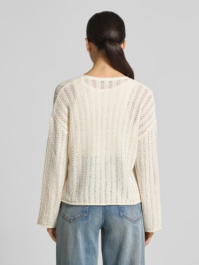 Kobieta modelka nosi Regular Fit Strickjacke mit Lochstrickmuster von Tom Tailor Denim, kremowy kolor, wzór ażurowy, długi rękaw, widok całej sylwetki z tyłu.