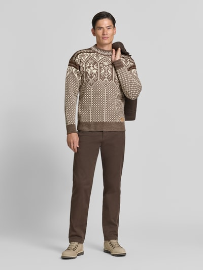 Männermodel trägt Strickpullover mit Stehkragen von Dale of Norway in Beige-Braun mit geradem Schnitt, Ganzkörperansicht von vorne. Rückenlänge 66 cm, Ärmellänge 58 cm, überschnittene Schultern, Label-Patch, gerippte Abschlüsse.