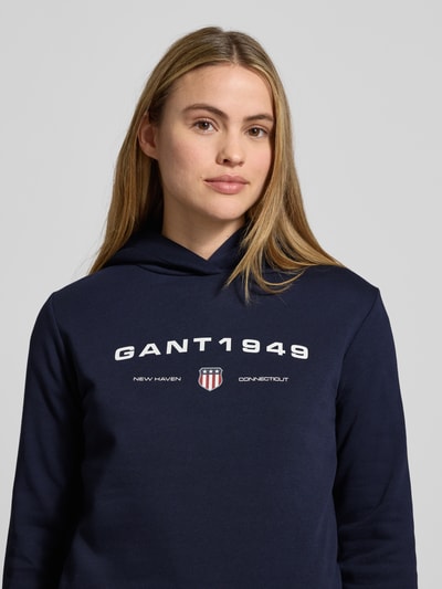 Frauenmodel trägt Regular Fit Hoodie mit Label-Print von Gant in Dunkelblau, Baumwoll-Mix, dezenter Label-Print, Nahaufnahme Oberkörper.