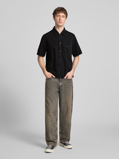Męski model nosi Relaxed Fit Jeanshemd aus Lyocell-Baumwoll-Mix von Marc O'Polo Denim, czarna koszula jeansowa, krótki rękaw, przód całej sylwetki.