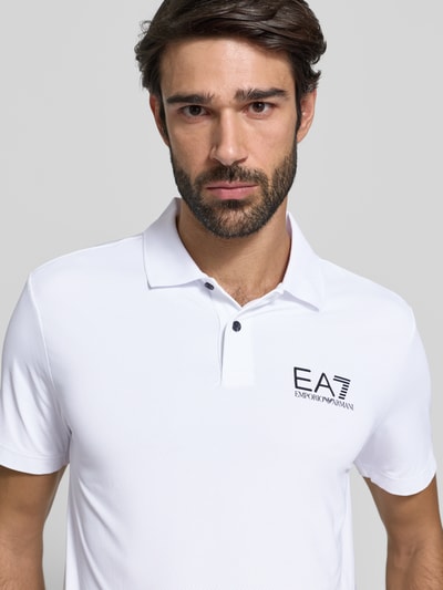 Männermodel trägt Regular Fit Poloshirt mit Logo von EA7 Emporio Armani, Material-Mix mit Stretch-Anteil, Polokragen, Knopfleiste, Logo, Rückenlänge 71 cm bei Größe M, Nahaufnahme Oberkörper.