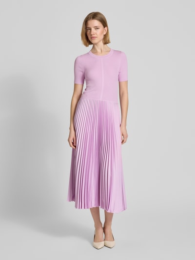 Vrouwenmodel draagt tailliertes Businesskleid aus Viskose-Mix Modell 'FADRIDI' van BOSS, effen look, taillering fit, midi-lengte, ronde hals, plissé-details, korte mouw, rechte zoom, pastel lila tinten, gladde en geplisseerde texturen. Volledige lichaamsaanzicht van voren.