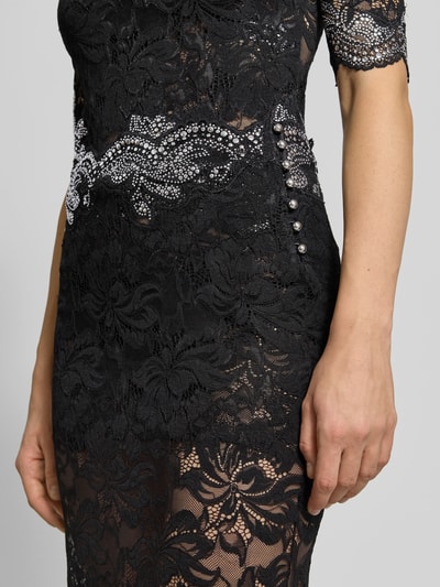 Vrouwenmodel draagt Midirok uit Spitze van Rabanne in zwart met semi-transparante kant, geschulpte zoom, recht pasvorm, detailopname. Context: dames midirok van Rabanne, elastische materiaalmix, semi-transparant design, muschelsaum, totale lengte maat 38: 38 cm, bandwijdte maat 38: 85 cm.