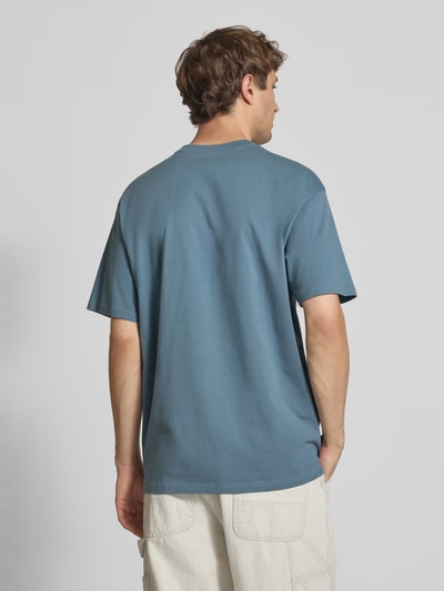 Männermodel trägt Herren T-Shirt mit Label-Stitching Modell 'Madison' von Carhartt Work In Progress, Reine Baumwolle, Regular-Fit, Farbe Blau, Rundhalsausschnitt, Rückenlänge bei Größe M 75 cm, Ganzkörperansicht Rückansicht.