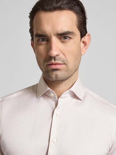 Männermodel trägt Slim Fit Business-Hemd in unifarbenem Design mit Kentkragen von OLYMP Level Five aus reiner Baumwolle, Nahaufnahme Oberkörper.