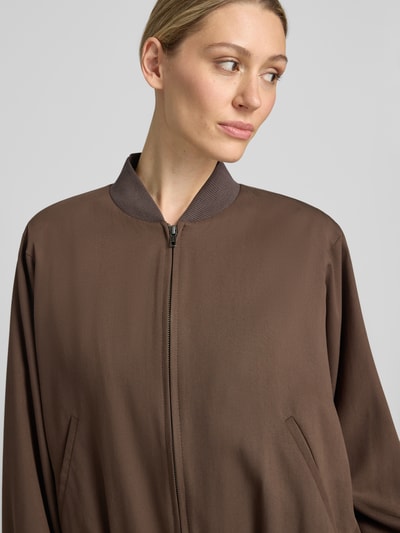 Frauenmodel trägt Blouson aus Lyocell-Mix mit Zweiwege-Reißverschluss von Drykorn in Braun, Relaxed-Fit, Stehkragen, Eingrifftaschen, Nahaufnahme Oberkörper. Rückenlänge 55 cm, Brustweite 74 cm, Ärmellänge 60 cm bei Größe 36.