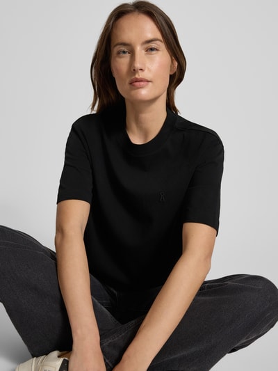 Frauenmodel trägt T-Shirt mit Label-Stitching Modell 'TARJAA' von ARMEDANGELS, unifarben schwarz, lockerer Schnitt, Nahaufnahme Oberkörper.