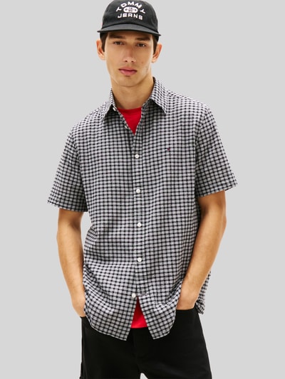 Männermodel trägt Regular Fit Freizeithemd aus Baumwoll-Mix von Tommy Jeans mit Optik:Allover-Muster, gestreift, Logo-Stitching, Ganzkörperansicht von vorne.