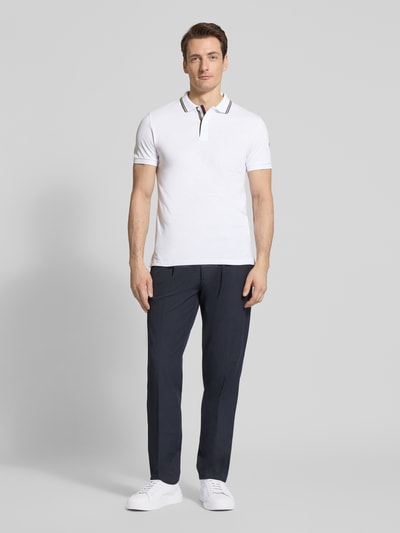 Männermodel trägt Slim Fit Poloshirt aus Baumwolle von Colmar Originals, weiß, Polokragen, Label-Details, Ganzkörperansicht von vorne.