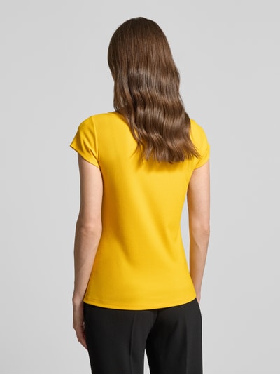 Kobiece model prezentuje T-Shirt mit Cut Out od Marc Cain, damski t-shirt z mieszanki modalu z dodatkiem streczu, prosty krój, drobne prążkowanie, okrągły dekolt, wycięcie, długość tyłu w rozmiarze 36: 56 cm, widok całej sylwetki z tyłu.