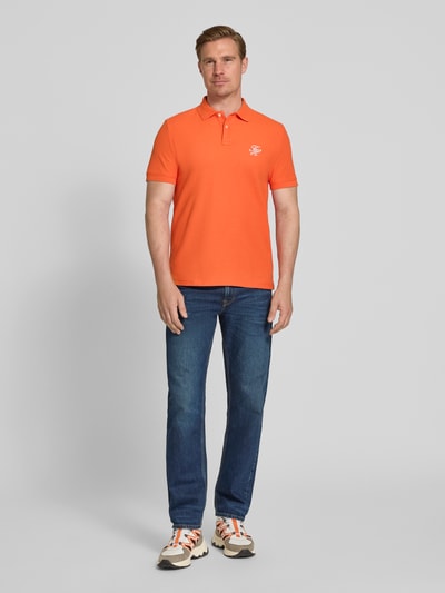 Męski model nosi Regular Fit Poloshirt aus reiner Baumwolle von Tommy Hilfiger, jednolity kolor, krótkie rękawy, logo, bawełna pikowana, widok całej sylwetki z przodu.