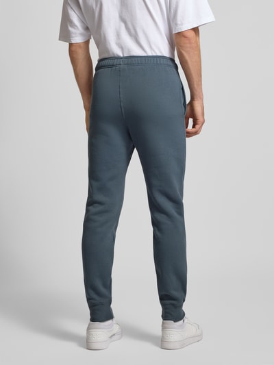 Männermodel trägt Sweatpants mit elastischem Bund und Label-Stitching von CHAMPION aus Baumwoll-Mix, Regular-Fit, Rückansicht.
