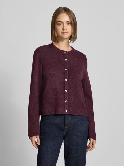 Frauenmodel trägt Loose Fit Strickjacke mit Rundhalsausschnitt Modell 'SIMONI' von ONLY in dunklem Rot, Jeans, Ganzkörperansicht von vorne, Damen Strickjacke von ONLY.