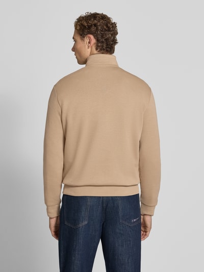Mężczyzna nosi Regular Fit Troyer aus Baumwoll-Mix von Polo Ralph Lauren w kolorze beżowym, granatowe dżinsy, Ganzkörperansicht Rückansicht.