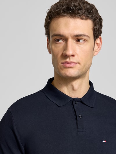 Mężczyzna model nosi Regular Fit Poloshirt aus Baumwolle von HECHTER PARIS w kolorze granatowym, detal z logo, kołnierzyk polo, długość tyłu w rozmiarze M: 66 cm, koszulka polo, krój regular fit, bawełna, Nahaufnahme górnej części ciała