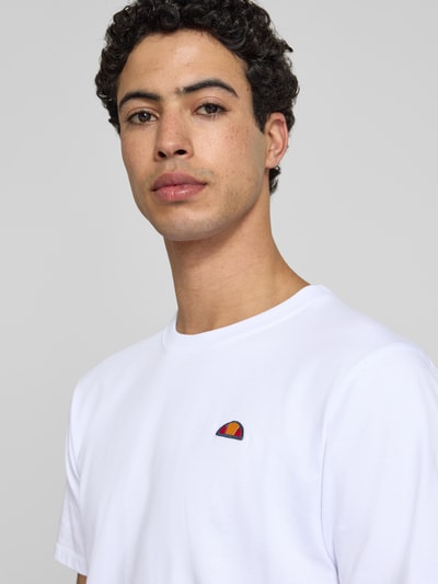 Męski model nosi T-Shirt mit Label-Stitching Modell 'CASSICA' od Ellesse z czystej bawełny, prosty krój, okrągły dekolt, wyhaftowane logo, długość tyłu w rozmiarze M: 71 cm, zbliżenie na górną część ciała.