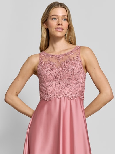 Frauenmodel trägt Abendkleid mit floralem Spitzenbesatz von Laona in Rosa, Ziersteinbesatz, semitransparente Optik, ärmelloses Design, taillierte Passform, Nahaufnahme Oberkörper. Rückenlänge bei Größe 36: 142 cm, Brustweite: 32 cm.