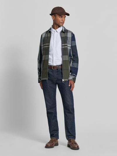 Męski model nosi koszulę casualową Tailored Fit Freizeithemd aus reiner Baumwolle Modell 'STRIPED OXFORD' von Barbour, efekt: wzór na całej powierzchni, krój tailored fit, kołnierzyk typu button down, listwa guzikowa na całej długości, fakturowany wzór, wyhaftowane logo, długi rękaw, sportowe mankiety z regulacją, wykończenie: oxford, materiał: bawełna, kolor biały, jeansy, brązowy pasek, brązowe buty, czapka, całopostaciowe ujęcie z przodu.