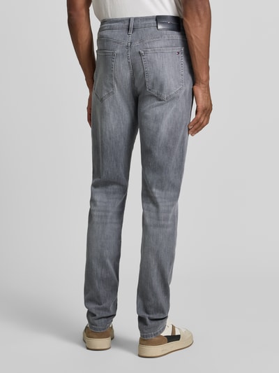 Męski model nosi Slim Fit Jeans aus Baumwoll-Mix Modell 'BLEECKER' od Tommy Hilfiger w szarym kolorze, faktura gładka, Ganzkörperansicht Rückansicht.