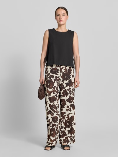 Frauenmodel trägt Stoffhose aus Viskose-Mix mit Eingrifftaschen Modell 'KARINA' von KARINA, floral gemustert, Wide Fit, Ganzkörperansicht von vorne.