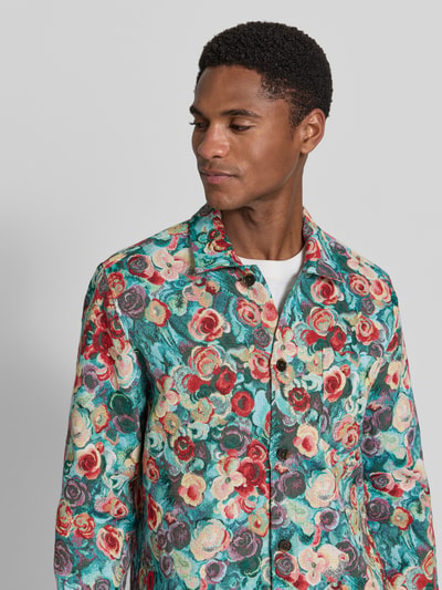 Męski model nosi Regular Fit Overshirt im Allover-Look von Les Deux z mieszanki bawełny, wzór na całej powierzchni, kołnierzyk typu kent, listwa guzikowa, długość tyłu w rozmiarze M: 74 cm, kolorowy wzór kwiatowy, faktura materiału widoczna, Nahaufnahme górnej części ciała.
