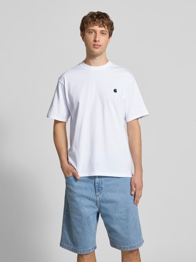 Männermodel trägt Herren T-Shirt mit Label-Stitching Modell 'Madison' von Carhartt Work In Progress in Weiß aus Reine Baumwolle, Regular-Fit, Rundhalsausschnitt, Rückenlänge bei Größe M 75 cm, Ganzkörperansicht von vorne.