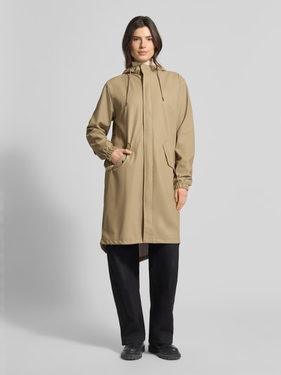 Frauenmodel trägt Regular Fit Parker mit Kapuze Modell 'Fishtail' von Rains in Beige mit Pattentaschen, elastischen Ärmelabschlüssen, Ganzkörperansicht von vorne, Details: Rückenlänge 104 cm, Schulterbreite 45 cm, Brustweite 55 cm, Ärmellänge 65 cm bei Größe S.