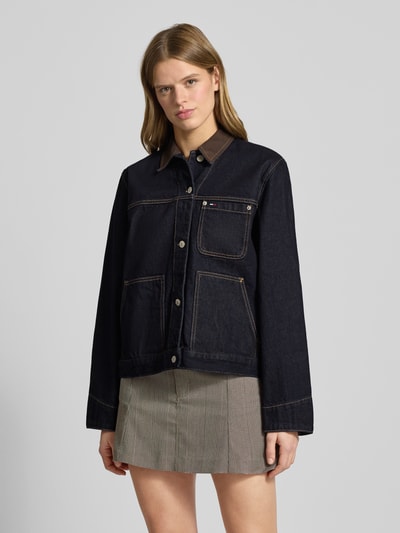 Frauenmodel trägt Oversized Jeansjacke aus reiner Baumwolle von Tommy Jeans in dunklem Denim mit Kontrastnähten und Label-Stitching, Ganzkörperansicht von vorne.