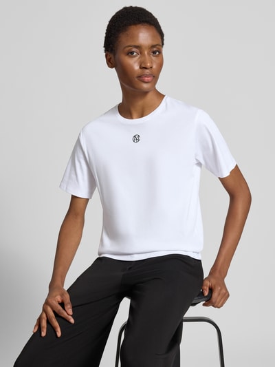 Kobiece model prezentuje Damski t-shirt Regular Fit T-Shirt aus reiner Baumwolle Model 'Melea' von MSCH Copenhagen, biały z nadrukiem z logo, okrągły dekolt, krój regular fit, bawełna, długość tyłu w rozmiarze XS/S: 57 cm, zdjęcie w ujęciu na górną część ciała z przodu