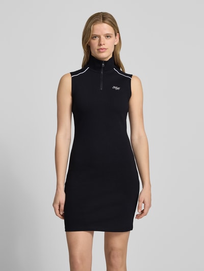 Frauenmodel trägt Körpernahes Jersey-Kleid aus Baumwoll-Mix Modell 'NUZIPPO_B' von Hugo Blue in Optik: Unifarben mit Kontraststreifen, Mini-Länge, Hochgeschlossen, Label-Stitching, Verschluss: kurzer Reißverschluss, Ärmelform: Ohne Ärmel, Materialverarbeitung: Jersey, Material: Baumwoll-Mix, Ganzkörperansicht von vorne.