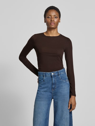 Frauenmodel trägt dunkelbraunes Slim Fit Langarmshirt aus Lyocell-Mix Modell 'AVA' von VERO MODA, kombiniert mit blauer Jeans, Ganzkörperansicht von vorne. Damen Langarmshirt von VERO MODA.