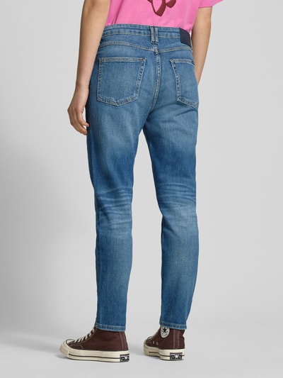 Frauenmodel trägt Slim Fit Jeans mit Stretch-Anteil Modell 'Freja' von Marc O'Polo in Blau mit Used-Look, 5-Pocket-Design, Label-Patch, Bio-Baumwolle und Elasthan, Knopf-Reißverschluss, Ganzkörperansicht Rückansicht.
