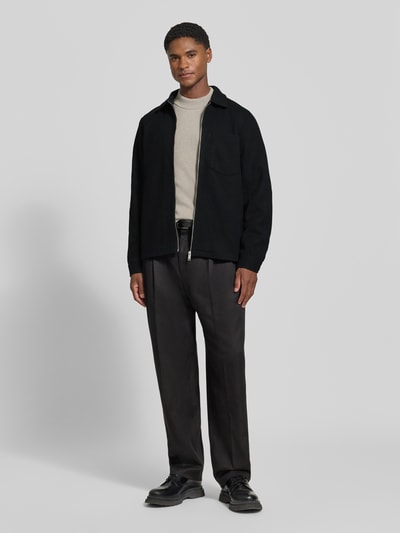 Männermodel trägt Jacke mit Brusttasche und Kentkragen Modell 'ROLFSTED' von Casual Friday in Schwarz, Ganzkörperansicht von vorne. Gerader Schnitt, Reißverschluss, schlichte Textur, Teil der Herrenmode-Kollektion, Rückenlänge 62 cm, Schulterbreite 42 cm, Brustweite 51 cm, Ärmellänge 66 cm.