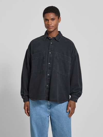 Männermodel trägt Relaxed Fit Jeanshemd mit Kentkragen Modell 'JAZY' von American Vintage aus Reine Baumwolle in Schwarz mit Brusttaschen, Ganzkörperansicht von vorne, Kontext: Rückenlänge bei Größe M/L 81 cm, Schulterbreite 67 cm, Ärmellänge 58 cm.