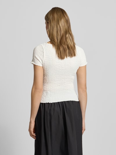 Frauenmodel trägt Slim Fit T-Shirt mit Strukturmuster Modell 'Alora' von Noisy May, cremeweiß, Elastischer-Material-Mix, Kurzärmelig, U-Boot-Ausschnitt, Rückenlänge bei Größe S: 50 cm, Ganzkörperansicht Rückansicht.