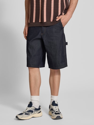Männermodel trägt Baggy Fit Jeansshorts Modell 'ARAGON' von Redefined Rebel aus Reine Baumwolle mit Eingrifftaschen, Nahaufnahme Oberschenkel. Bundweite 50 cm, Innenbeinlänge 33 cm in Größe M.