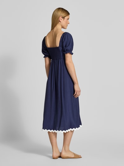 Frauenmodel trägt Tunikakleid mit Karree-Ausschnitt von Apricot in Dunkelblau, A-Linie, Midikleid, 1/2-Arm, Rückansicht Ganzkörperansicht. Rückenlänge bei Größe S: 120 cm, Brustweite bei Größe S: 40 cm, Ärmellänge bei Größe S: 30 cm, elastische Ärmelabschlüsse, weißer Saum.