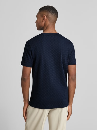 Männermodel trägt T-Shirt mit geripptem Rundhalsausschnitt von JOOP! Collection aus reiner Baumwolle, Regular-Fit, Rückenlänge 68 cm, Ganzkörperansicht Rückansicht.