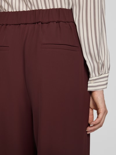 Frauenmodel trägt Wide Fit Hose mit Gesäßtaschen von Jake*s Collection in Dunkelrot, Teilelastischer Bund, Nahaufnahme Rückansicht.