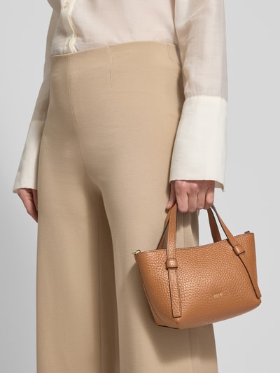 Kobiece model prezentuje Handtasche mit Label-Detail Modell 'COSMO' od Abro w kolorze jasnobrązowym, faktura ziarnista, szerokość 23 cm, długość 14 cm, głębokość 10 cm, odpinany pasek 127 cm, detal z logo, widok z przodu, zbliżenie na torebkę.