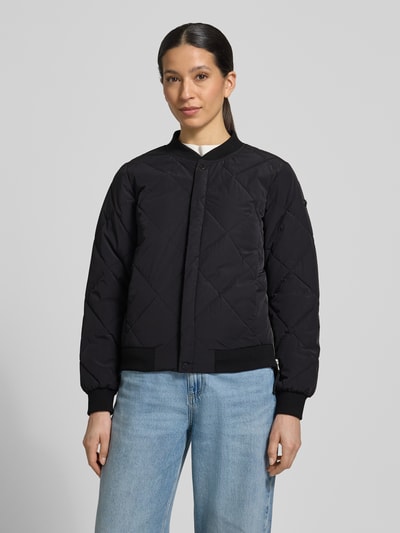 Frauenmodel trägt schwarze Steppjacke mit Knopfleiste Modell 'ANGE2' von khujo, Regular-Fit, Stehkragen, Ganzkörperansicht von vorne. Rückenlänge bei Größe S: 59 cm, Schulterbreite: 36 cm, Brustweite: 46 cm, Ärmellänge: 61 cm.
