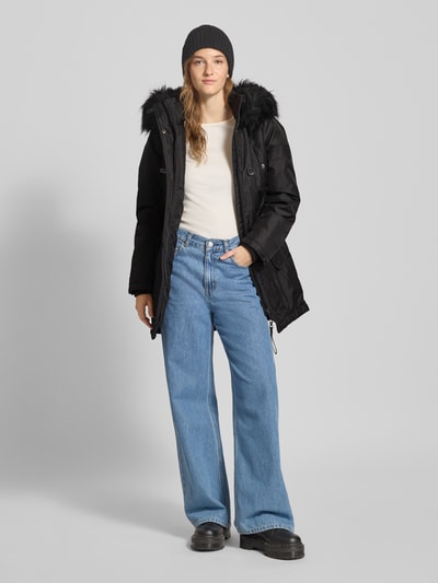 Vrouwenmodel draagt Shaped Fit Parka met Label Patch model 'IRIS' van Only, zwart, regular fit, capuchon met imitatiebont, zij- en borstzakken, lange mouwen, storm cuffs, uni kleur, volledige vooraanzicht.