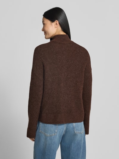 Frauenmodel trägt braune Regular Fit Strickjacke aus Woll-Mix Modell 'SIA' von Selected zu blauen Jeans, Ganzkörperansicht Rückansicht, Damen Strickjacke von Selected.