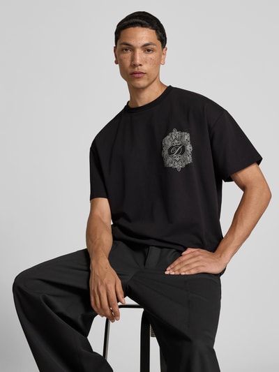 Männermodel trägt Regular Fit T-Shirt aus Baumwoll-Mix von Don´t Waste Culture, Schwarz, Label-Detail, Kurzärmelig, Nahaufnahme Oberkörper.